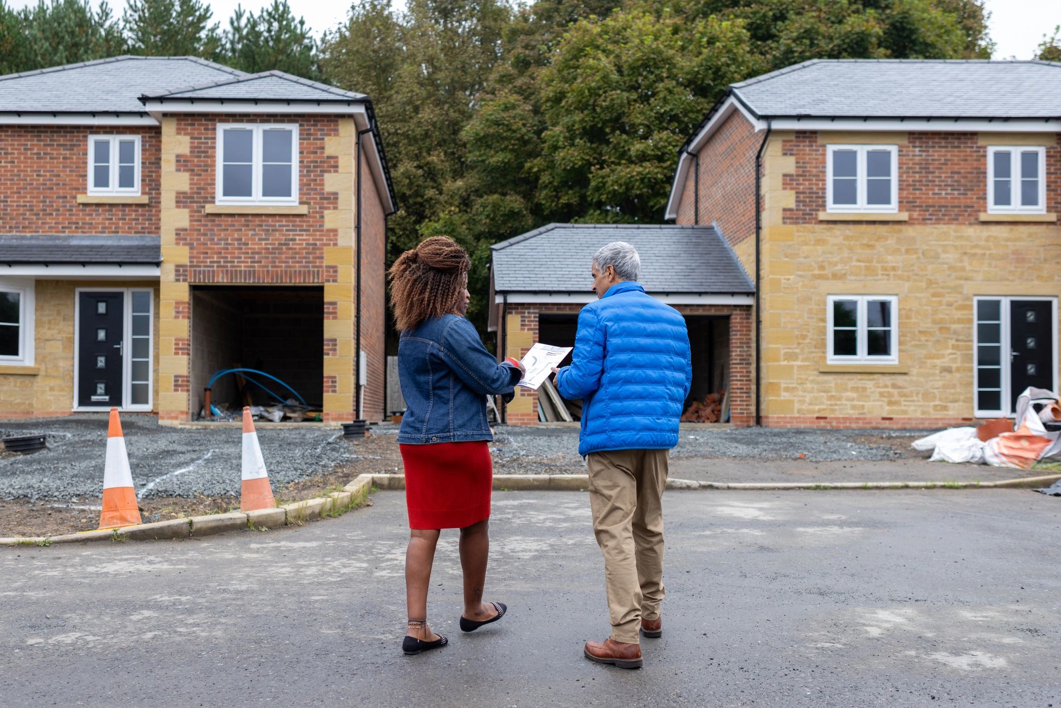 Real estate professional reviewing plans with a homeowner at a housing site